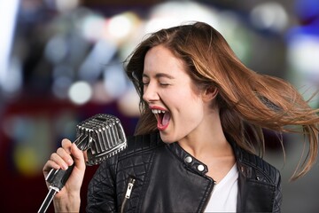 A young happy woman singing in karaoke. - obrazy, fototapety, plakaty