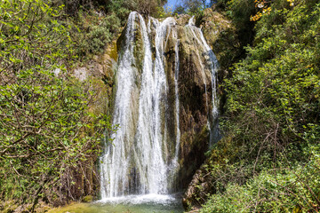 Fototapeta na wymiar A beautiful waterfall in the mountains on the island of Corfu in Greece. A tourist spot for nature lovers. 