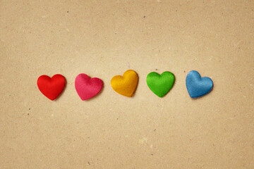 Hearts in different colors on recycled paper background - Concept of love and inclusion