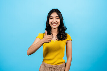 Portrait, Asian women wearing t-shirt, stood smiling with an expression admiration be happy with what is in front, gave thumbs up in appreciation, Isolated indoor studio on blue background.