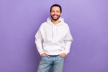 Portrait of cheerful nice person toothy smile put hands pockets posing isolated on purple color background