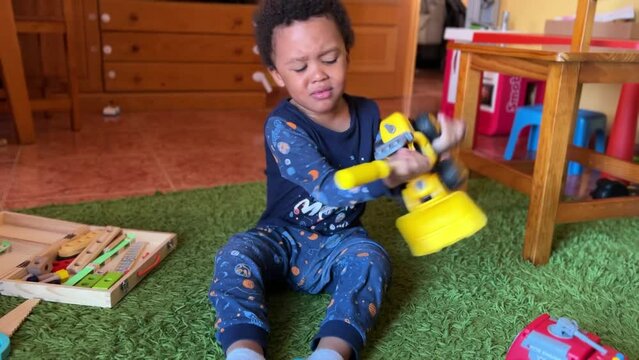 Scene of a 3-year-old cute black  child playing at home to fix his toy, losing patience, thowing it and getting angry.