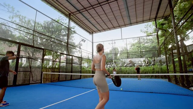 A lot of people play tennis outdoor court. Young adult player serve ball opponent. Racket sport game match. Team hit workout outside arena. Sportsman health care. Woman person fit exercise. Girl train
