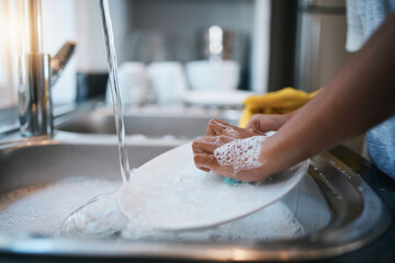 Hands, sink and cleaning dishes with a person in the kitchen of a home to wash a plate for hygiene....