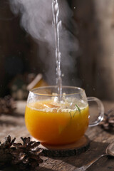 Tea with herbs, berries and fruits in a transparent cup on a wooden background
