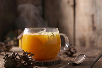 Tea with herbs, berries and fruits in a transparent cup on a wooden background