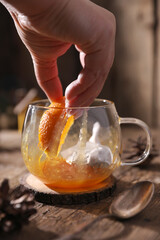 Tea with herbs, berries and fruits in a transparent cup on a wooden background