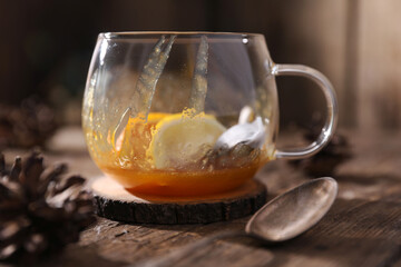Tea with herbs, berries and fruits in a transparent cup on a wooden background