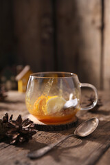 Tea with herbs, berries and fruits in a transparent cup on a wooden background
