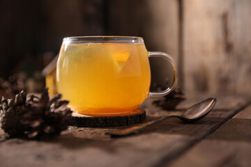 Tea with herbs, berries and fruits in a transparent cup on a wooden background