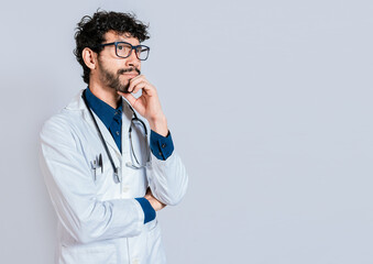Young doctor thinking and looking up isolated. Pensive doctor man looking up isolated, Doctor thinking with hand on chin