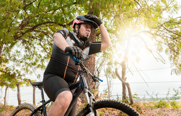 Exhausted chubby cyclist on his bike looking into the distance. Tired cyclist while riding the bike...