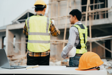 Engineering people and contractor wearing safety helmet on construction site holding blueprint in...
