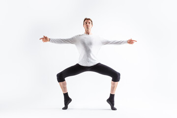 Caucasian Handsome Young Man Dancing Ballet Posing in Stretching Pose with Lifted Hands in White Shirt On White.