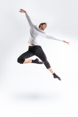 Fototapeta na wymiar One Active Professional Caucasian Handsome Young Athlete Man Posing in Flying Ballet Pose with Lifted Hands in White Shirt On White.