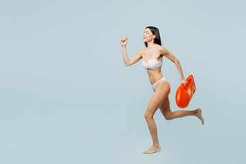 Full body young young lifeguard woman in swimsuit near hotel pool hold in hand lifebuoy run fast...