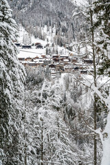 Fototapeta na wymiar Snowfall in Sauris. Among the woods and historic houses.