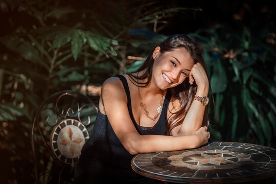 beautiful young Latina woman sitting at a table with jungle type background