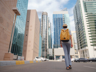 travel to the United Arab Emirates, Happy young asian female traveler with backpack and hat in downtown street of Abu Dhabi. Vacation and tourist destination concept.