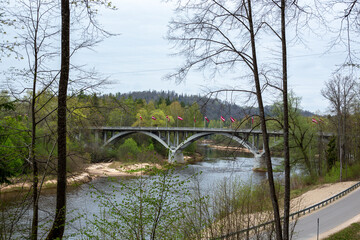 Bridge over river Gauja with national flags of Latvia in Sigulda in Latvia in end of April