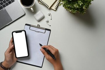 Above view of manumitting at workplace and using mobile phone. Blank screen for advertising text message