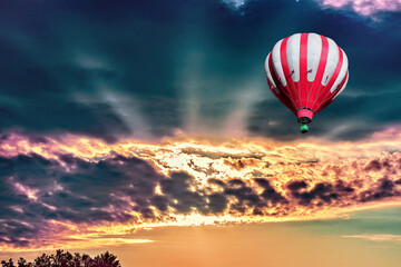 A bright hot air balloon on the background of bright orange sunset.