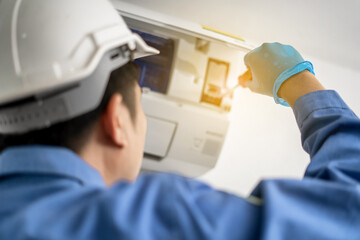 A maintenance air conditioner technician uses a drill to clean the air conditioner inside the house.