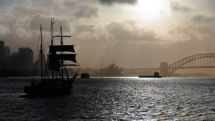 Silhouetted schooner barque tall ship sailing towards Harbour Bridge in a hazy afternoon. Sydney-Australia-562