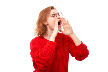 Portrait of redhead young woman screaming into her palms on white studio background. Important information, news concept