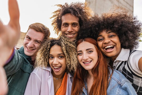 Multiethnic guys and girls taking selfie outdoors in backlight - Happy lifestyle friendship concept about multicultural young people having fun together