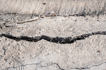 A deep crack in the concrete extending into the distance. The concept of infrastructure destruction, crisis phenomena.