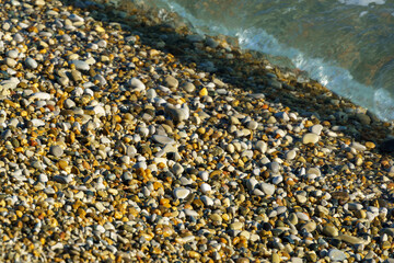 Sea pebble against the backdrop of the blue sea at sunset on beach and under water of Black Sea coast as nature background