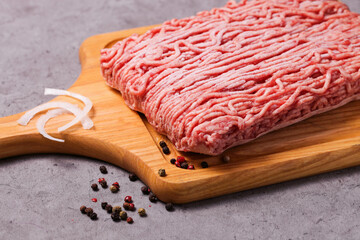 Frozen minced meat with spices on wooden cutting board