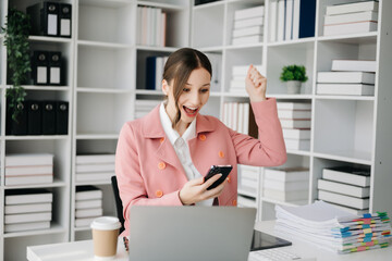 Caucasian business woman are delighted and happy with the work they do on their tablet, laptop and taking notes at the office.