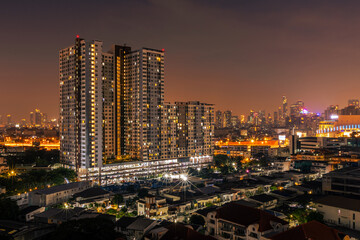 Fototapeta premium The high angle background of the city view with the secret light of the evening, blurring of night lights, showing the distribution of condominiums, dense homes in the capital community