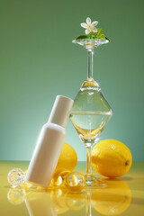 Template for cosmetic advertising with white bottle unlabeled beside are glass cups and fresh lemon, crystal ball decorated on green background. Lemon extract concept