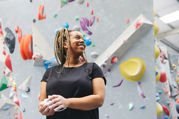 Smiling Woman Rubbing Hands With Chalk Ready For Climbing Wall At Indoor Centre