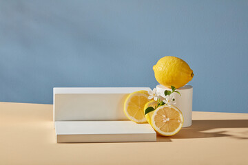 Minimal scene for display cosmetic - white podiums on blue background with fresh lemon, slices and...