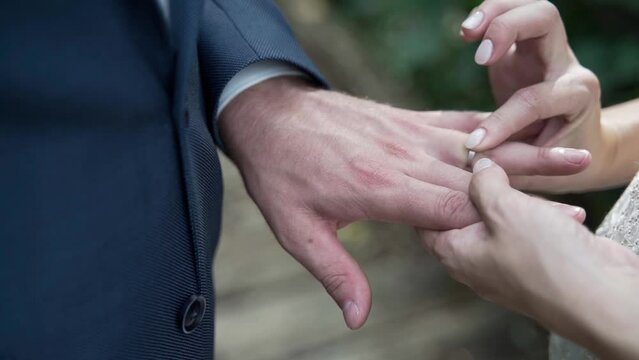 The bride puts the ring on the groom's finger, close-up of hands. hands of the groom and bride