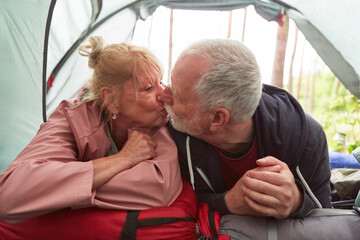 Senior couple kissing on mouth in camping tent