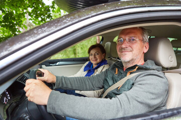 Senior man wearing seatbelt driving car during road trip