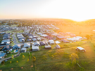 Aerial view at sunset over houses at the edge of town with paddock farmland backyard