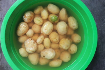 peeled potatoes soaked in water in a green plastic container