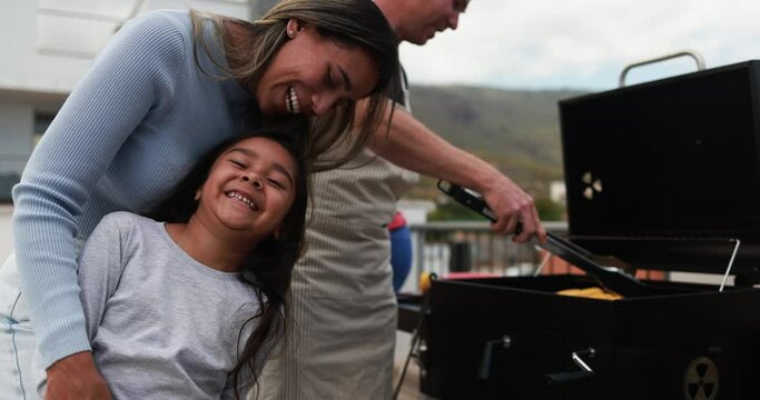 Multi generational family people doing barbecue during weekend day at home's rooftop - Latin mother and daughter smiling on camera - Summer dinner concept
