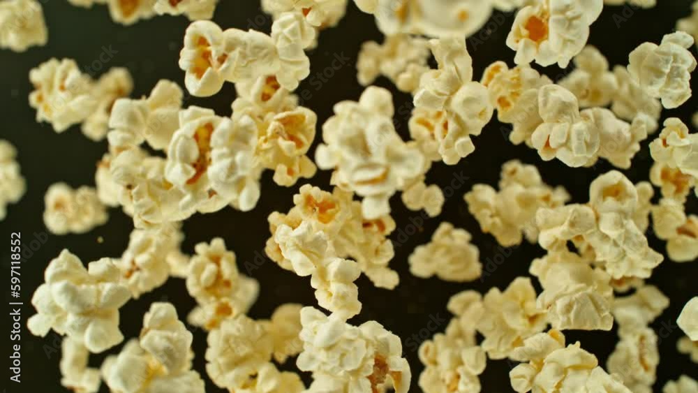 Poster super slow motion of rotating popcorn in the air. isolated on black background. filmed on high speed