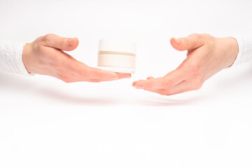 Mock-up of beautiful woman's hand holds round jar or container of cosmetic product cream or lotion on white isolated background. Concept of beauty, spa industry, skin care. Close-up, copy space