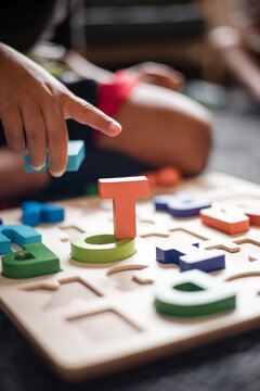 hand of Aboriginal boy playing with alphabet letter puzzle pieces