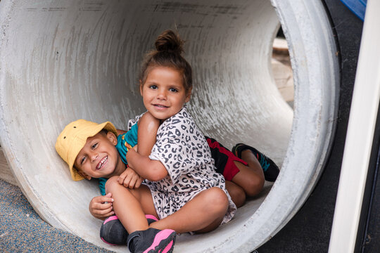 Young First Nations girl and boy playing together in a tunnel