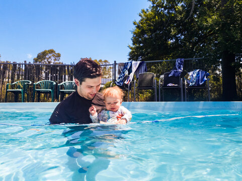 Young father in pool with baby in summer