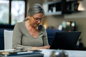 Fototapeta premium Senior mature older woman watching business training, online seminar on laptop computer remote working